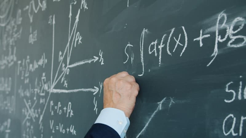 Main soulignant une équation mathématique sur un tableau noir